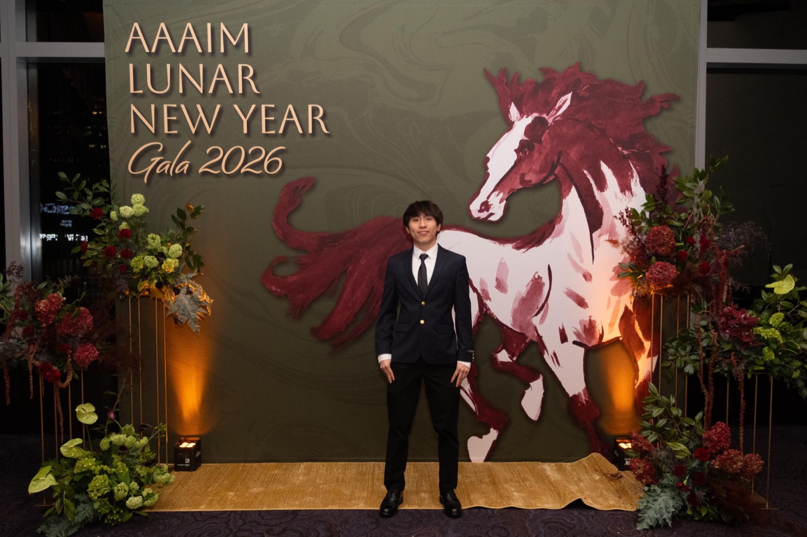 Yang in a suit at the AAAIM Lunar New Year Gala 2026 backdrop
